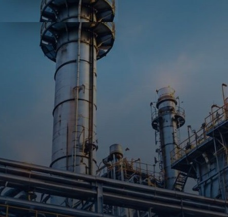 Industrial refinery towers and piping at dusk