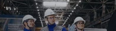 Three engineers in safety helmets inside an industrial facility